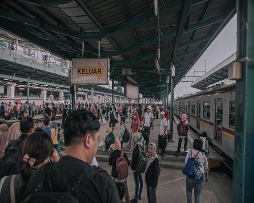 indonesian man doing light neck stretch while waiting for public transport